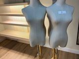 two mannequins sitting on a stand in a room