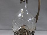 an image of a glass vase with a metal handle on a table