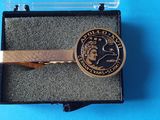 une pince à cravate dans une boîte sur laquelle est posée une pièce de monnaie