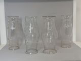 four glass vases sitting on a shelf in a room