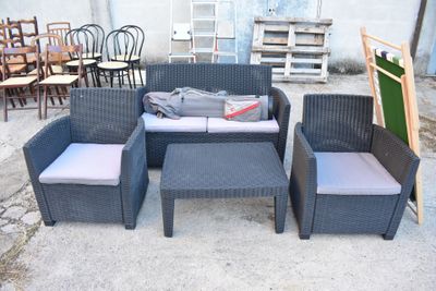 un canapé, un fauteuil, un pouf et une table basse dans un jardin