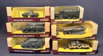 six véhicules militaires emballés dans des cartons, posés sur une surface grise