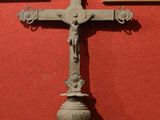 une croix posée sur un socle devant un mur rouge