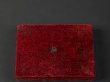 an old red box with a heart on it sitting on a black surface