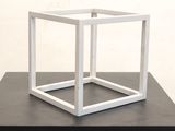 a white cube on a black table with a white wall in the background