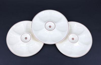 three white plates with gold rims sit on a black surface