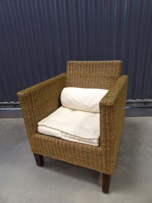 a wicker chair with pillows on it in front of a blue wall