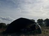 a tent in the middle of a field with trees in the background