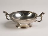 a silver bowl with handles and handles on a white surface