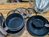 Plusieurs casseroles et poêles sont posées sur une table en bois.