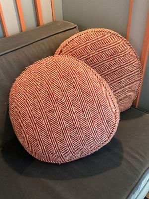 pair of orange herringle pillows sitting on a grey couch