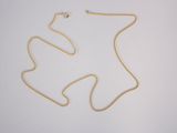 a gold chain with a small white bead on top of it