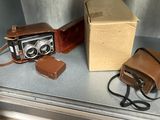 un appareil photo marron et un étui marron posés sur le rebord d'une fenêtre