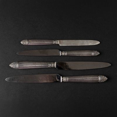 four knives and a knife holder on a black surface