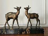 deux statues de cerfs posées sur un socle en marbre