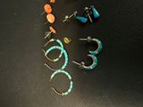 five pairs of earrings sitting on a black surface