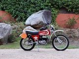 a red dirt bike parked next to a large rock