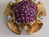 une image représentant une broche ornée de pierres roses et de diamants sur un fond blanc