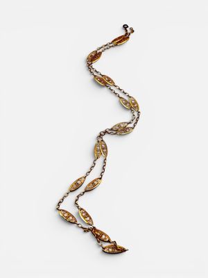a close up of a necklace on a white surface with a long chain