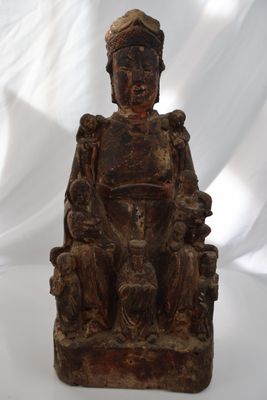 une vieille statue en bois représentant un homme assis sur une chaise
