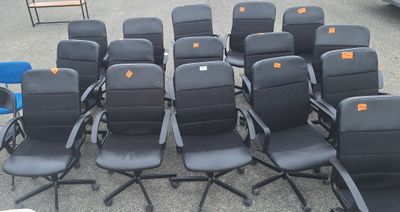 des rangées de chaises de bureau noires ornées d'étiquettes orange, dans un parking