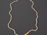 a white pearl necklace with a gold clasp on a black background