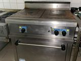 une cuisinière qui se trouve dans une cuisine, à côté d'un plan de travail