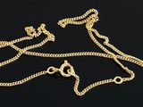 two gold chains and a necklace on a black surface