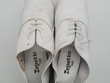 pair of white leather shoes with laces on top of a white box