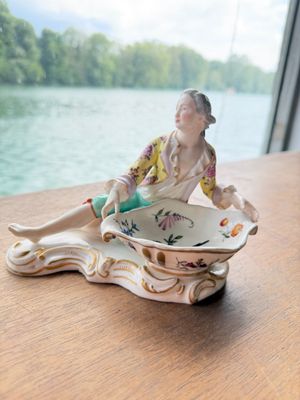 a figurine of a woman sitting in a bowl on a table