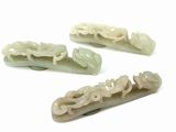 four pieces of carved jade hair clips on a white surface