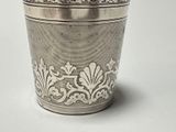 a silver cup with a design on it on a white surface