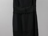 a black dress hanging on a hanger against a white wall