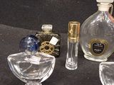 a bottle of perfume next to a glass bowl and a bottle of perfume on a table