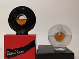 a small glass object on a black stand next to a red box