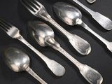 six cuillères et une fourchette sur une table noire
