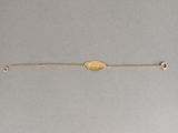 Gros plan sur un bracelet en or orné d'une pièce de monnaie