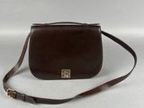 un sac à main en cuir marron muni d'un fermoir métallique et d'une bandoulière marron