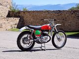 a dirt bike parked in a parking lot near a stone wall