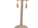 a pair of pink and gold earrings on a stand