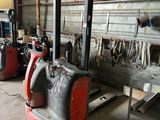 un chariot élévateur rouge dans un garage, à côté d'autres outils