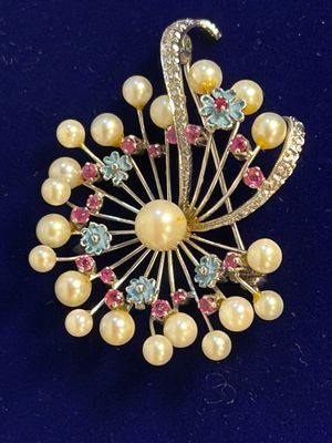 an image of a brooch with pearls and crystals on a blue surface