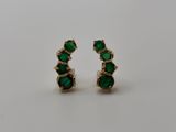 a pair of emerald earrings on a white background