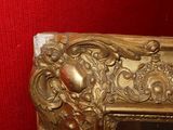 a mirror with a gold frame on a red wall