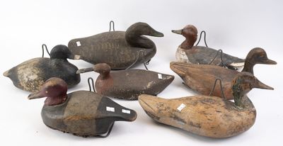 Plusieurs canards en bois sont alignés en rang sur une surface blanche