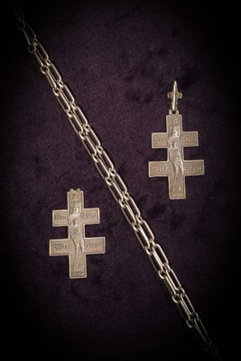 two silver crosses and a chain on a purple background