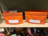 two bags of tea sitting on a shelf next to each other