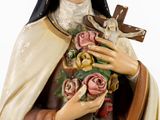 a statue of a woman holding a cross and flowers