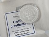 a silver coin sitting in a box with a certificate on it