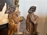 two figurines of jesus sitting on a table next to a bowl of fruit